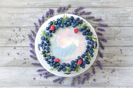 Lavender cake whit berries and flowers on a wooden background. Natiral light, natural colors