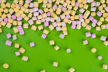 Marshmallows on green background with copyspace. Flat lay or top view. Background or texture of colorful mini marshmallows. Winter food background concept.の写真素材