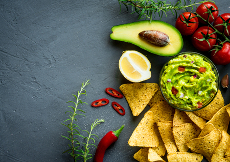 Guacamole bowl with ingredients and tortilla chips on a stone table. Top view image. Copyspace for your text.の写真素材