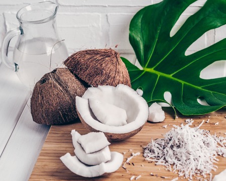 close up of a coconut the coconut chip and milk, monstera leaf, on a bamboo background. Fashion color filter.の写真素材