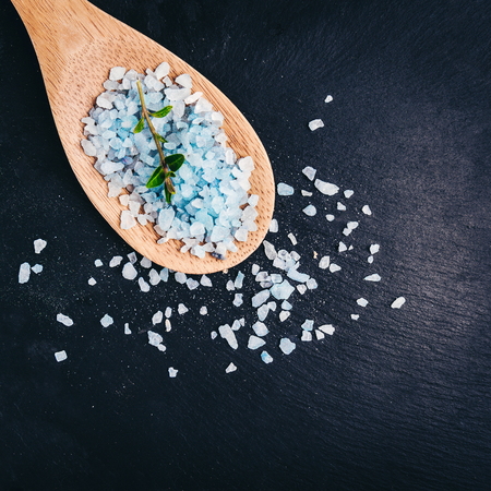 Blue spa aroma salt in bamboo spoon on black slate plateの写真素材