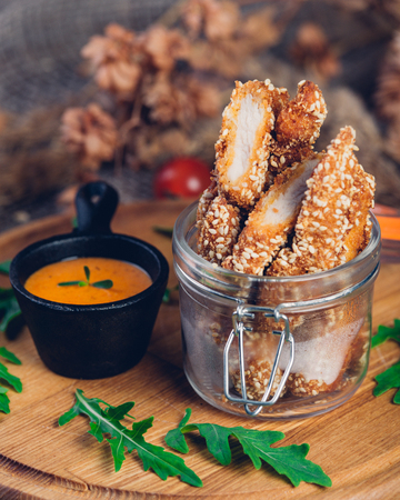 Chicken nuggets deep fried with sesame seeds with cheese sauce and arugula. Restaurant servingの写真素材