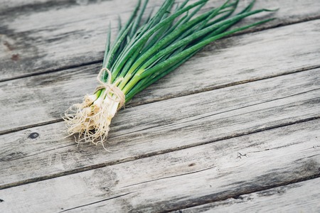 Fresh green onion on a wooden background. Top view. Free space for your textの写真素材