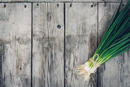 Fresh green onion on a wooden background. Top view. Free space for your textの写真素材