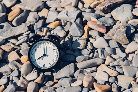 Vacation time. Alarm clock on the beach.の写真素材