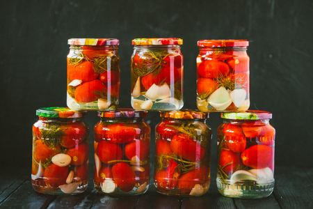 Several jars of canned tomatoes with ripe tomatoes and garlic.の写真素材