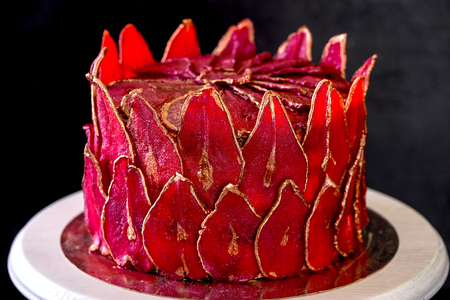 Chocolate cake with sliced red pears with gold, like a crown on the black background close-upの写真素材