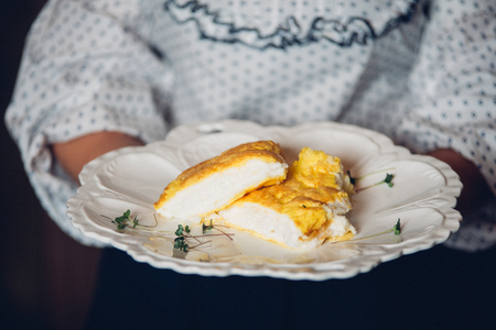 Women holding a plate with a lush Omelet in French. Omelet with cheese and milk.の写真素材