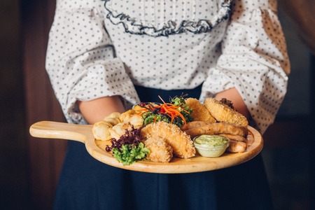 woman holding a plate of snacks for beer with different sauces on parchment.の写真素材