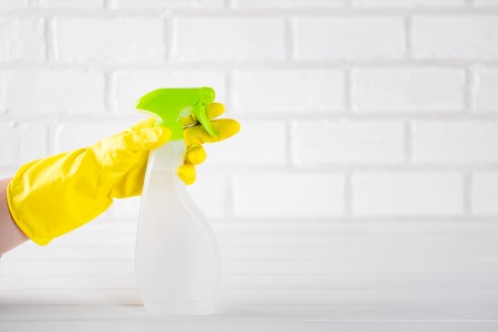hand holding a house-cleaning spray on an light background. Copy space