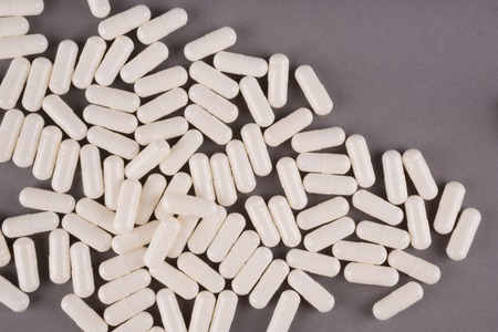White pills isolated on pastel coloured background. Medication and prescription pills flat lay...