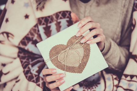 Female hands holding gift kraft box with heartの写真素材