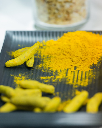 Turmeric Powder, Turmeric root on dark plate. Selective focus.
