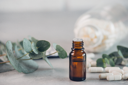 Eucalyptus essential oil and fresh leaves, white capsules pills on the stone boardの写真素材