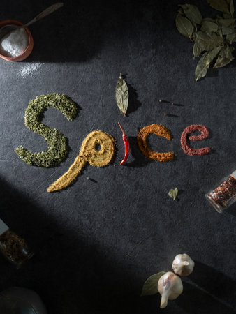 Various dry colorful spices on the table make up the word: Spice. food typography. View from above. dark backgroundの写真素材