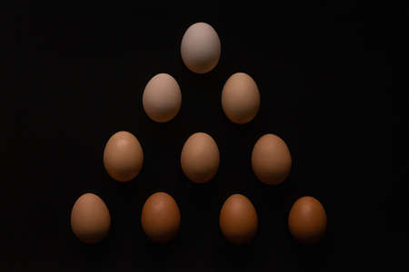 Eggs of different shades on a black background like a pyramideの写真素材