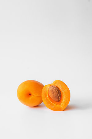 one whole apricot and half an apricot with a stone on a light background close-upの写真素材