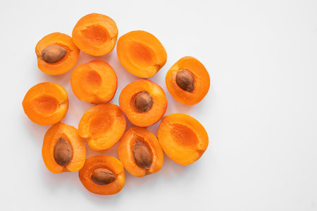 a bunch of apricots cut into halves on a light background, top view