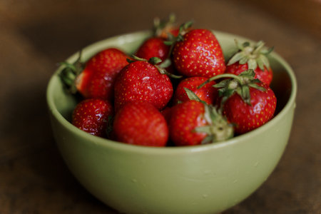 Strawberries in a green bowl on a wooden background. Selective focus.の写真素材
