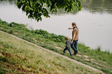 Father and son playing on the bank of the river in the parkの写真素材