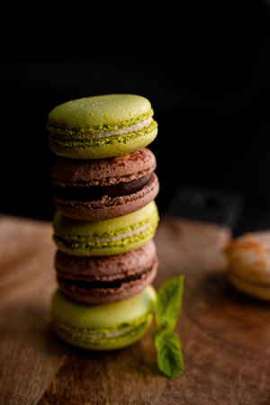 brown and green macaroons served on a wooden tray with mint leavesの写真素材