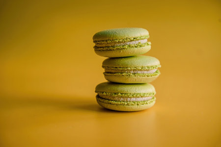 three green macaroons with pistachios on a colorful yellow backgroundの写真素材