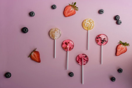 multi-colored homemade fruit lollipops lie on a white background next to various berries top viewの写真素材