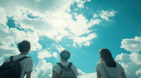 Three people are standing in the sky, looking up at the clouds. The sky is blue and the clouds are whiteの素材