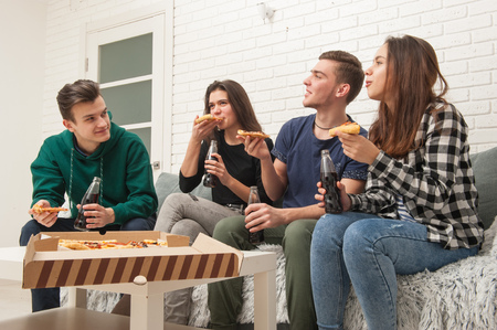A company of teenagers eating pizza