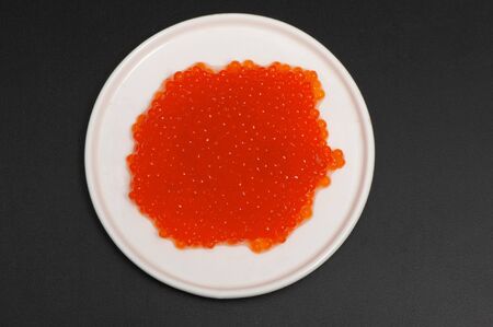 Red caviar in a saucer on a black backgroundの写真素材