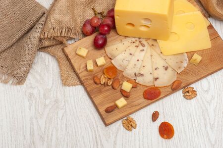 sliced walnut cheese on a board, grapes, dried apricots and nutsの写真素材