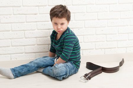 Offended boy and punishment by a beltの写真素材