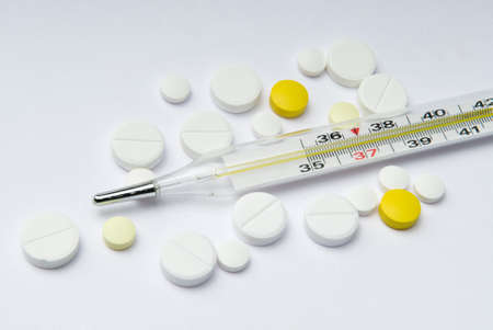 Thermometer and multicolored pills on white background