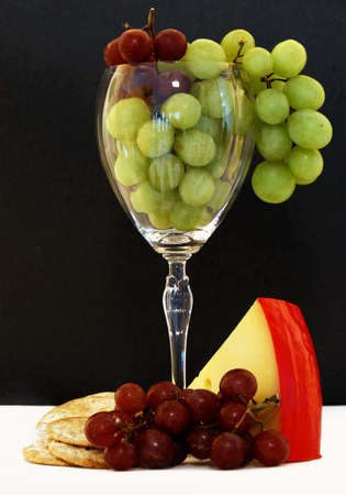 Grapes, crackers, and cheese in and around a wine glassの写真素材