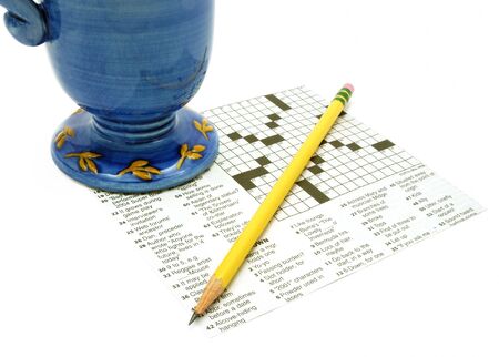 Blue and yellow mug and pencil on crossword puzzleの写真素材