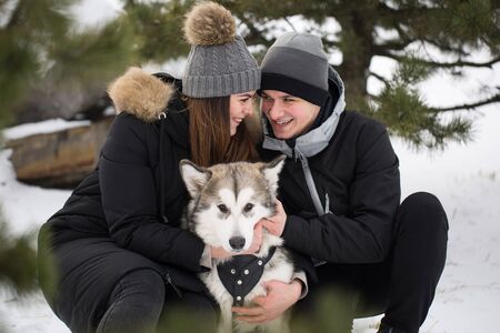 Beautiful family, a man and a girl in winter forest with dog. Play with the dog Siberian husky.