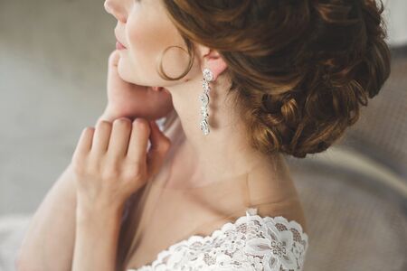 Beautiful bride posing in wedding dress in a white photo Studio. Mirror. Sofa. Bouquet. The door. Chandelier.の写真素材