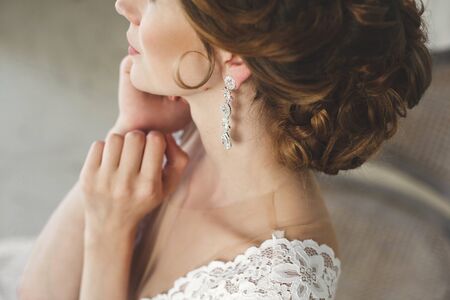 Beautiful bride posing in wedding dress in a white photo Studio. Mirror. Sofa. Bouquet. The door. Chandelier.