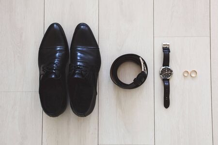 Accessories for the groom on the wedding day. Watches, rings, belt, shoes. The wooden surface.の写真素材