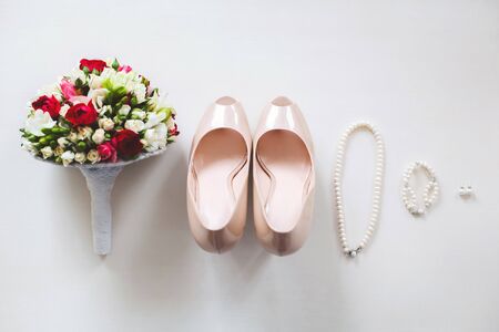 Wedding shoes cream color on a white table. Earrings. Bracelet. Necklace. The brides bouquet.の写真素材