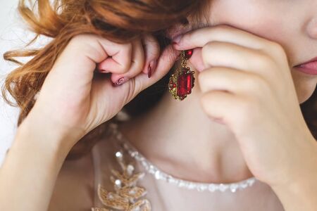 Wedding earrings on a female hand, she takes the earrings, the bride fees, morning bride, white dress, wear earringsの写真素材