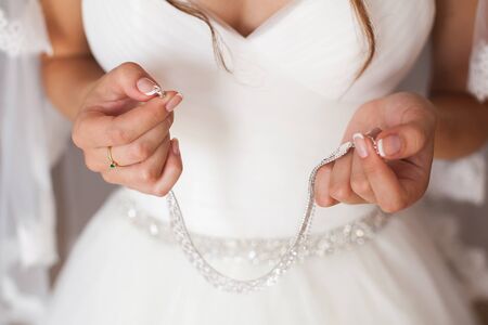 Beautiful bride is holding a necklace around her neck.の写真素材