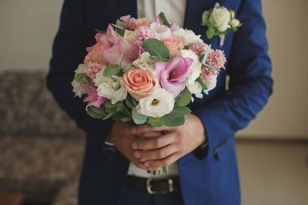 Beautiful wedding bouquet in hands of the groom.の写真素材
