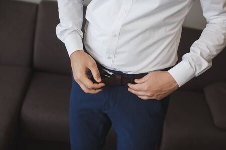 Man corrects belt, fees groom, mans hands, dressing, man buttons pants, jeans.