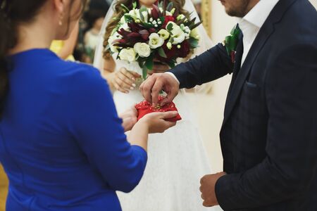 Newlyweds exchange rings, groom puts the ring on the bride's hand in marriage registry officeの写真素材