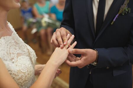 Newlyweds exchange rings, groom puts the ring on the bride's hand in marriage registry officeの写真素材