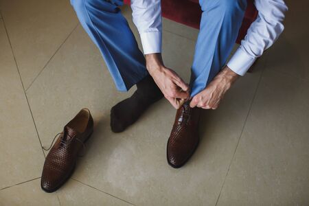 Mans hands tying shoelace of his new shoes. People, business, fashion and footwear concept - close up of man leg and hands tying shoe laces.の写真素材