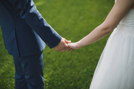Bride and groom walking together holding their handsの写真素材