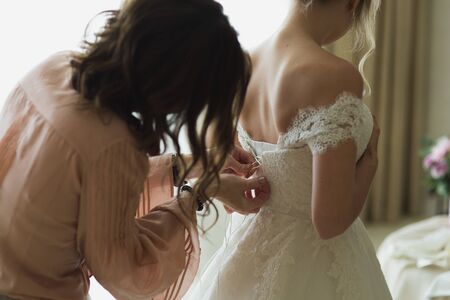 Bridesmaid is helping the bride to dress.の写真素材