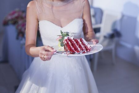 A piece of wedding cake in the hands of the bride